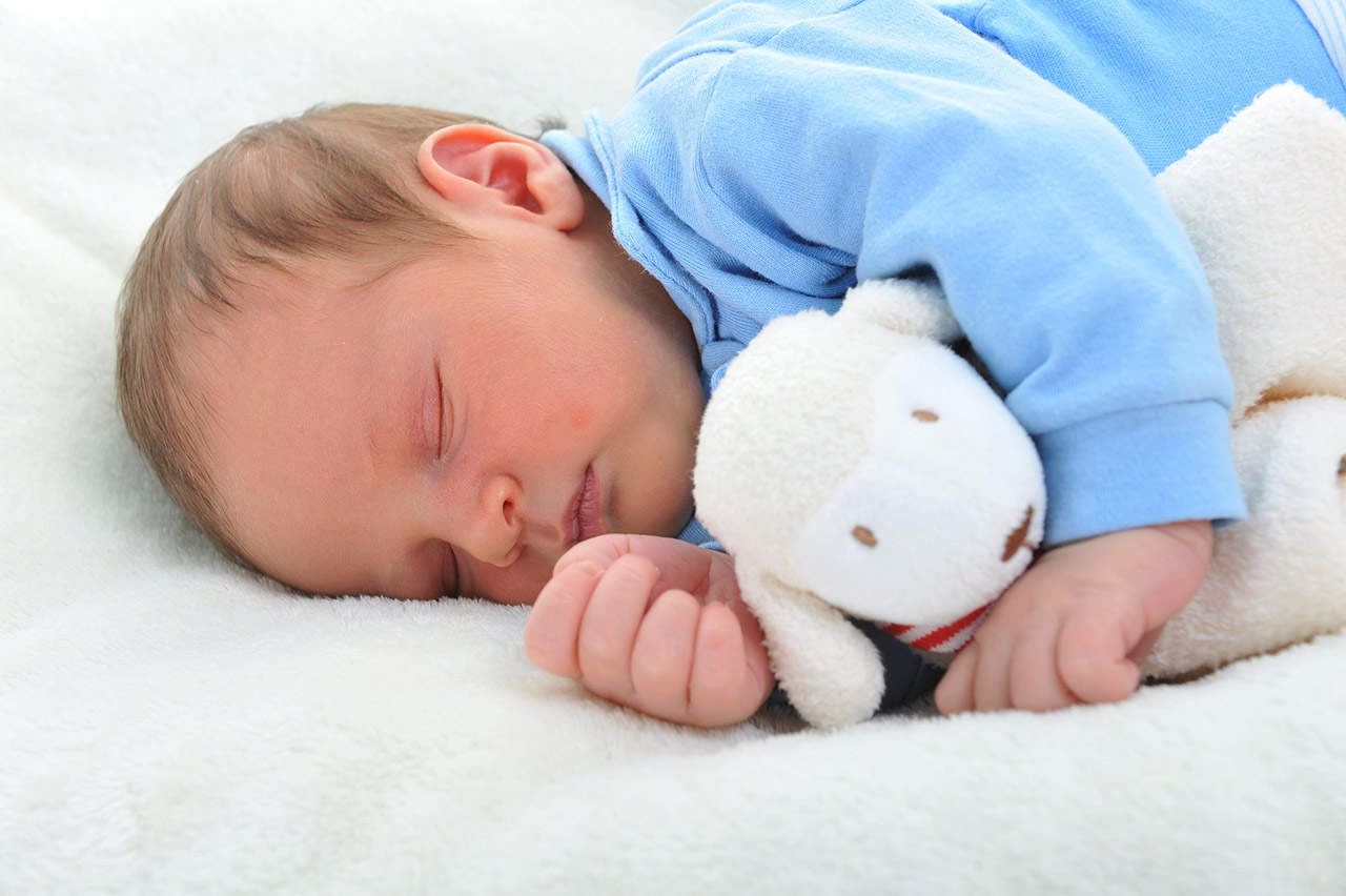 cute baby with toy sleeping on white blanket